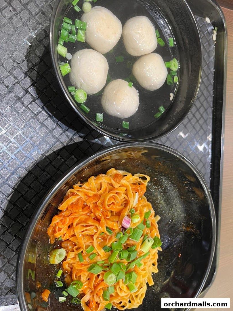 A bowl of Teochew fishball noodles with a side of fishballs in broth.