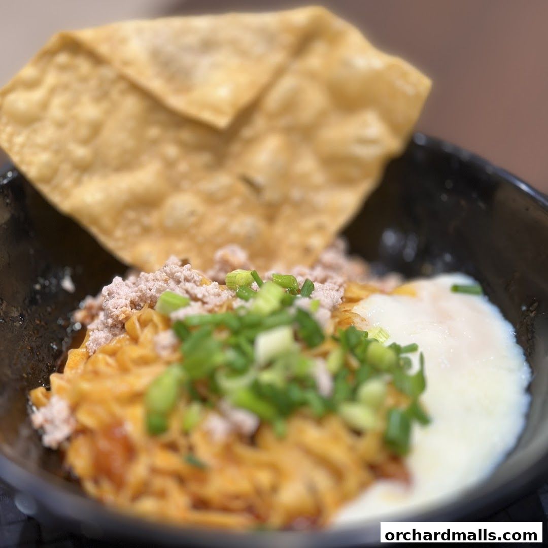 A close-up of a bowl of Teochew fishball noodles with minced meat and a soft-boiled egg.