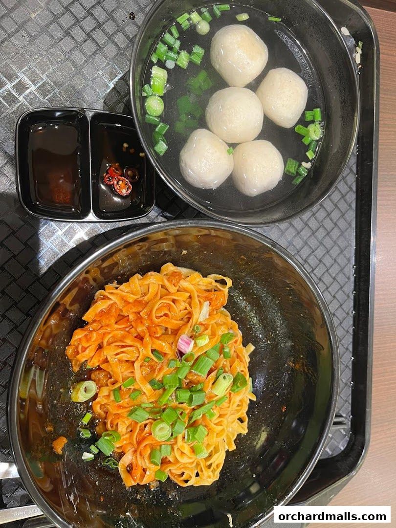 A bowl of Teochew fishball noodles with a side of dipping sauce.