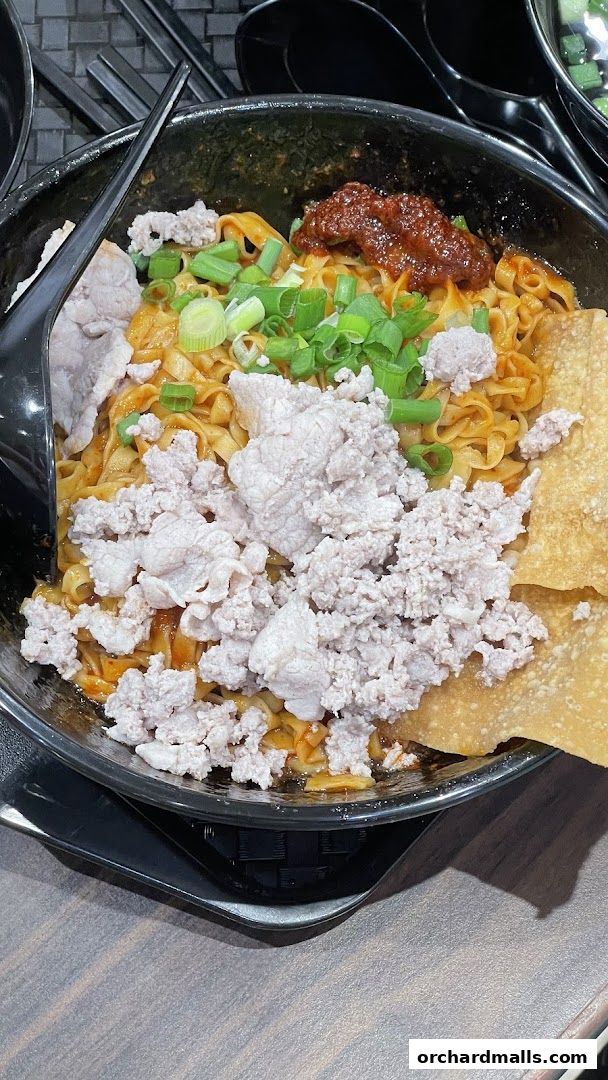 A close-up of a bowl of Teochew fishball noodles with minced pork and chili paste.