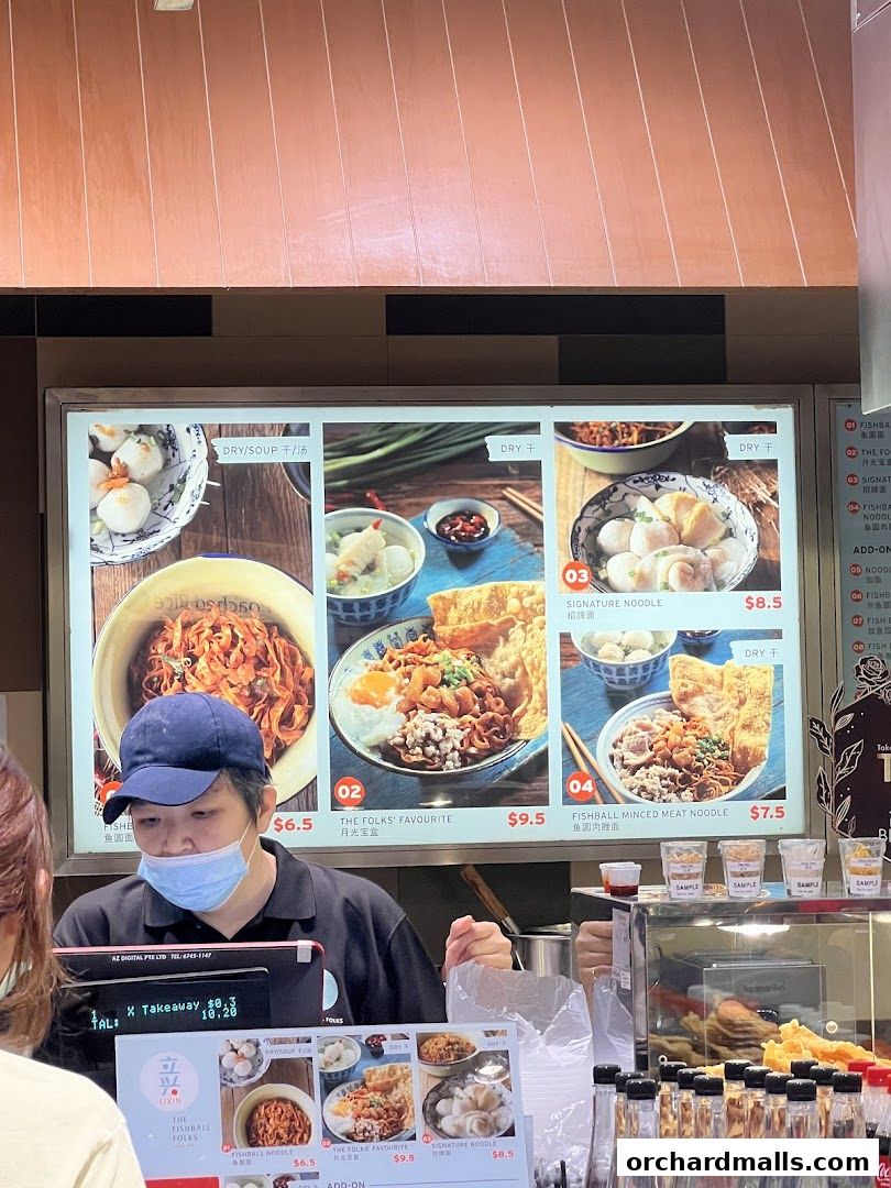 A digital menu board displays various fishball noodle dishes with prices and images.