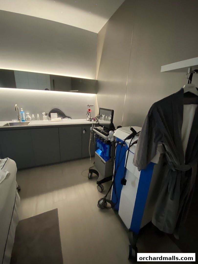 A clean, modern treatment room with medical equipment and a robe hanging.