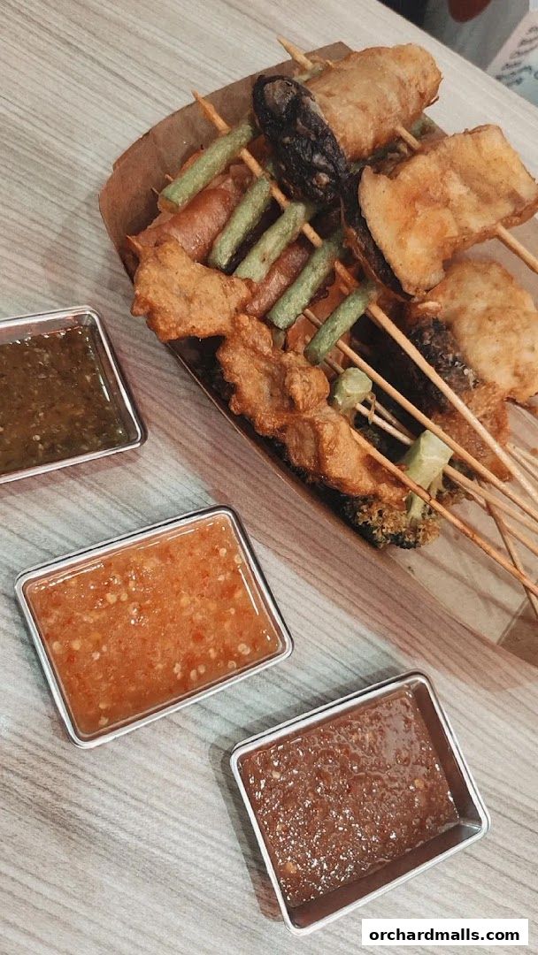 A platter of assorted fried skewers with three dipping sauces.