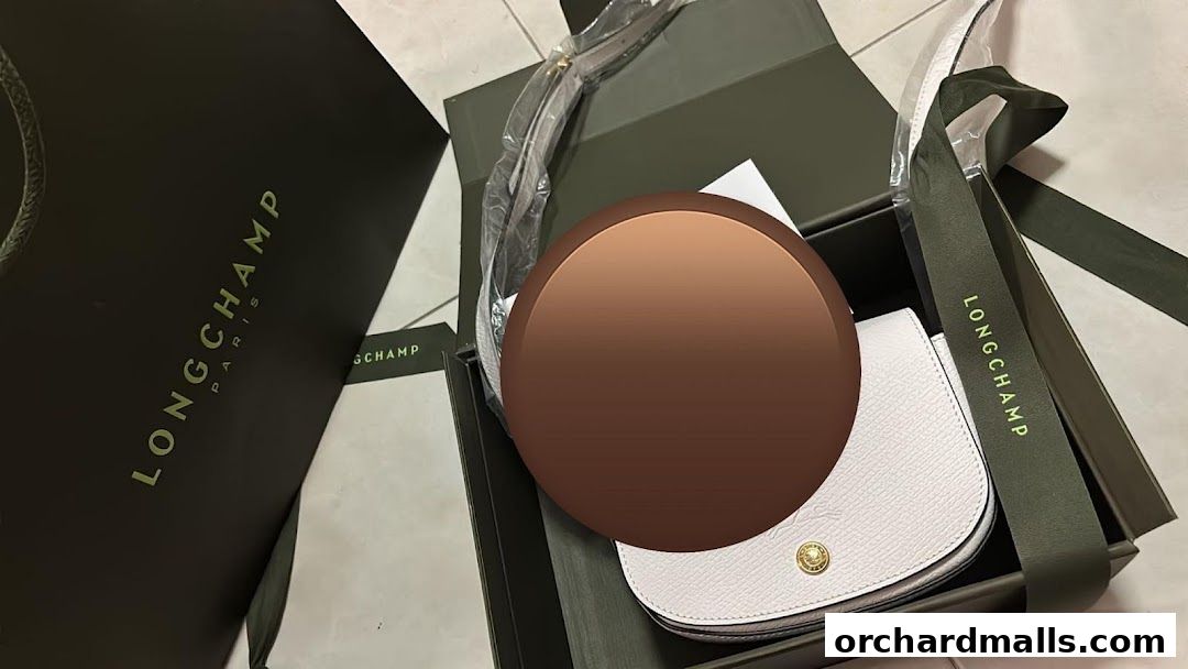 A white Longchamp handbag is presented in its original packaging with branded shopping bags.