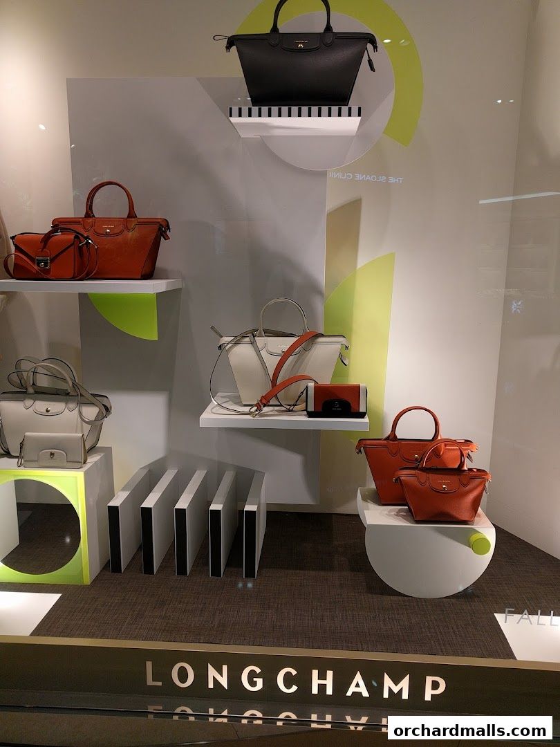 A Longchamp store window display featuring various handbags in different colors and sizes.