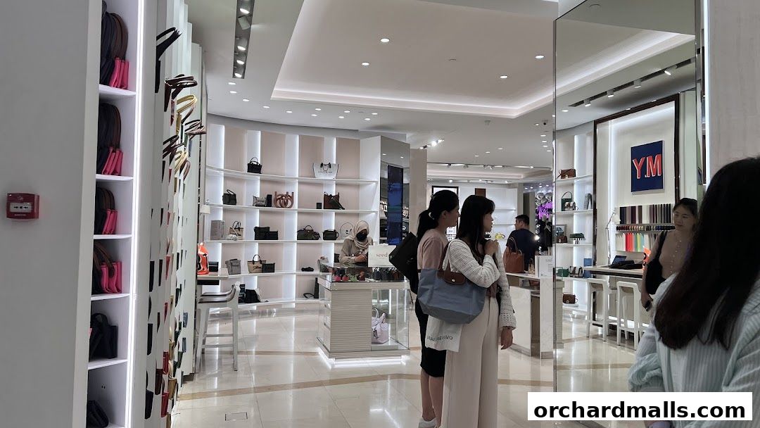 Interior view of a Longchamp store showcasing handbags and accessories with customers browsing.