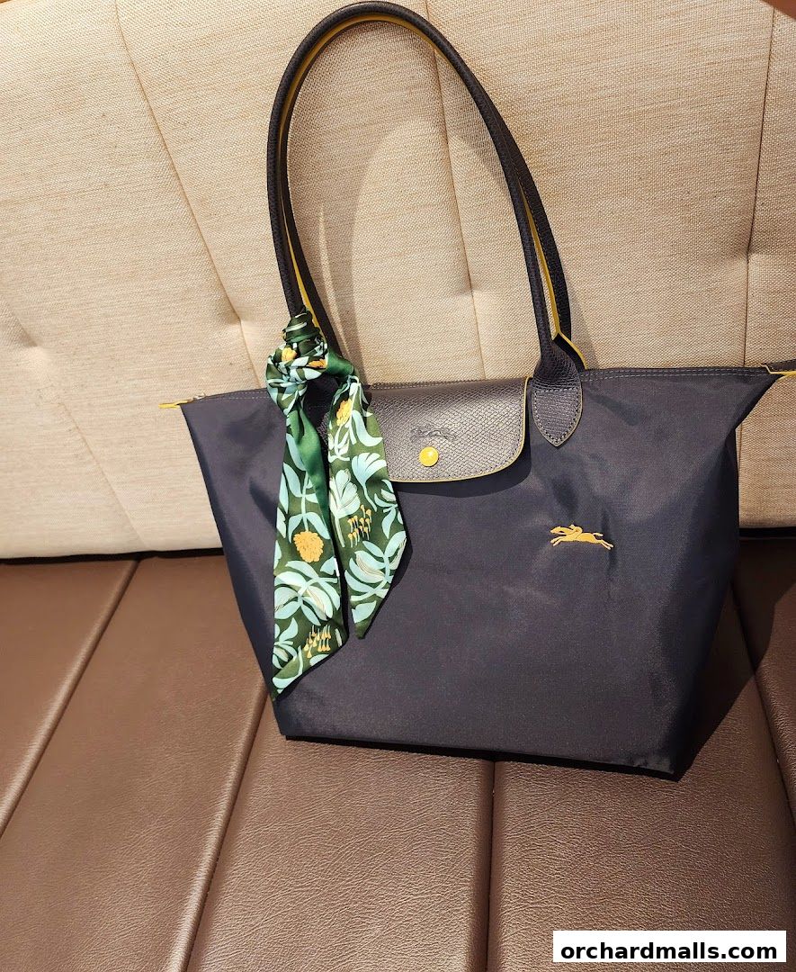 A dark blue Longchamp tote bag with a patterned scarf tied to the handle.