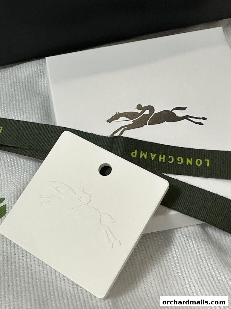 A close-up of Longchamp branding with a ribbon and embossed tag.