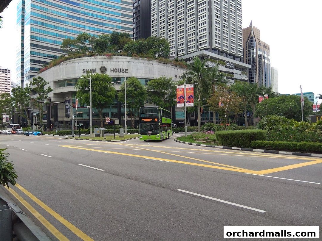 A street view of the Shaw House building with a double-decker bus on the road.