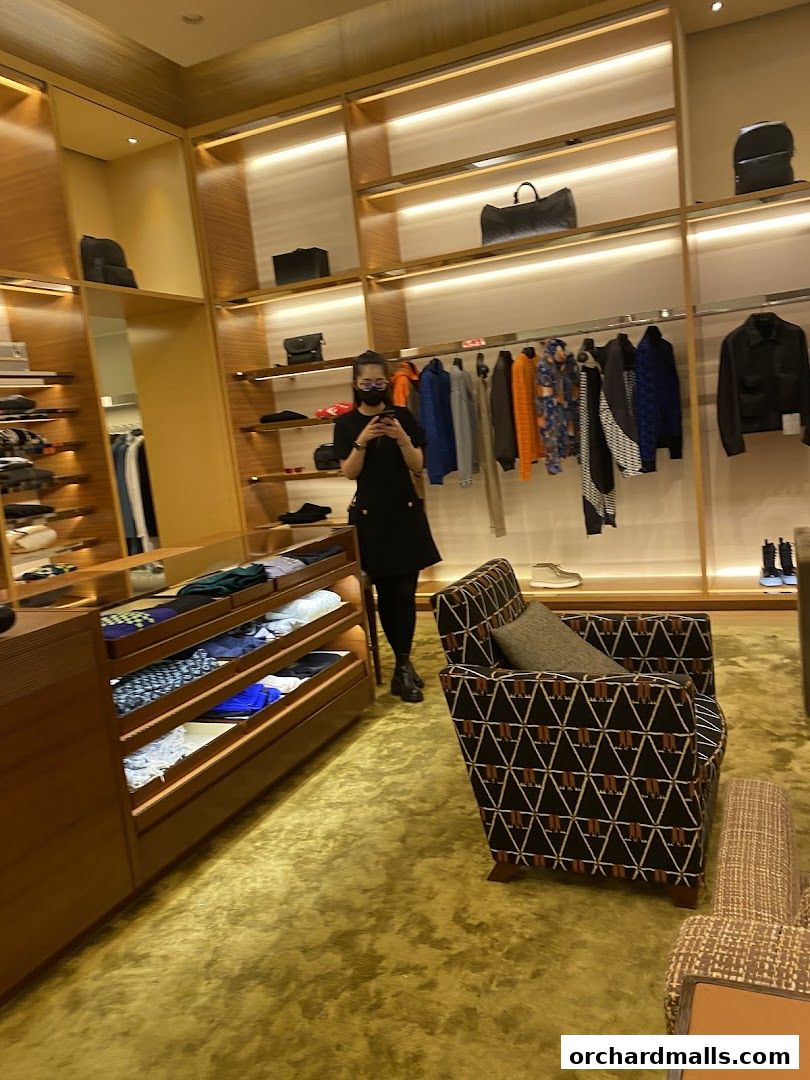Interior of a Louis Vuitton store with clothing, bags, and seating.