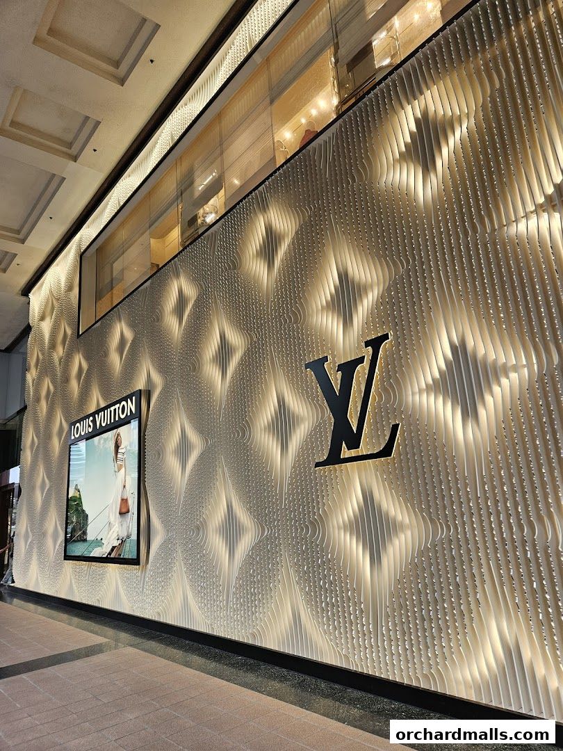 The illuminated facade of a Louis Vuitton store with its iconic logo and a fashion advertisement.