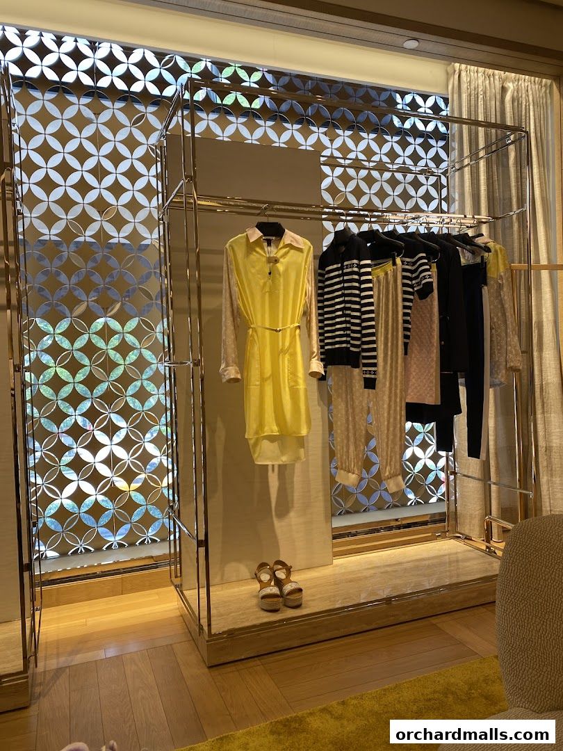 Louis Vuitton store interior displaying a yellow dress, striped tops, and pants on a rack.