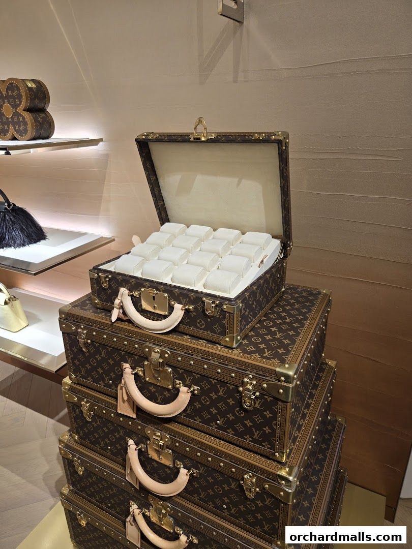 Louis Vuitton monogrammed trunks stacked, one open displaying watch cushions.