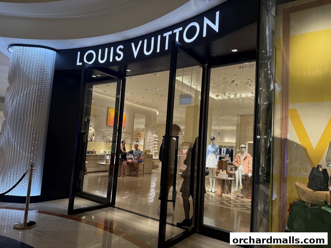 The entrance of a Louis Vuitton store with mannequins and merchandise displayed inside.