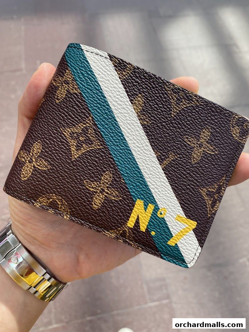 A hand holds a Louis Vuitton wallet with the iconic monogram and a distinctive stripe.