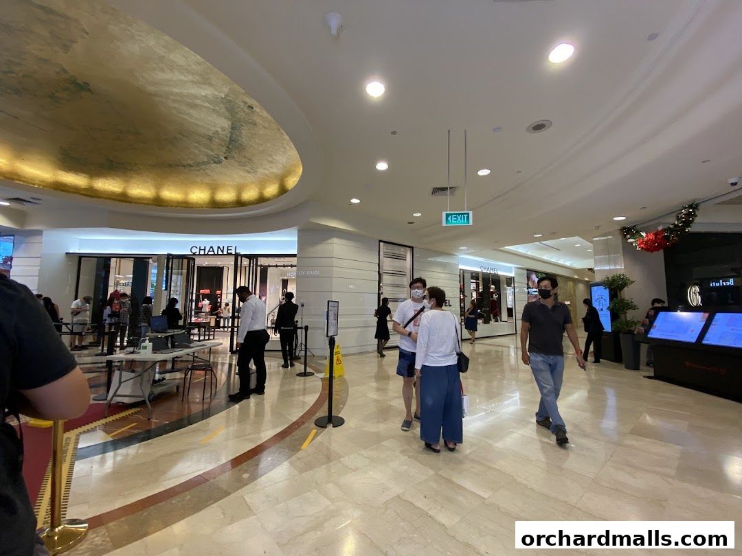 People queuing outside a luxury fashion store, Chanel, in a mall.