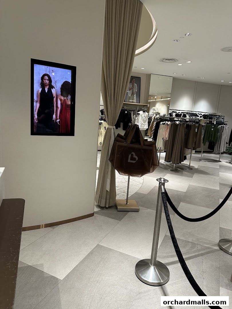 Interior view of a clothing store with racks of apparel and a digital display.