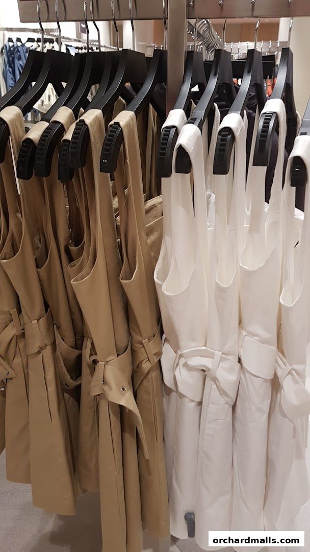 A rack of women's sleeveless dresses in beige and white colors.