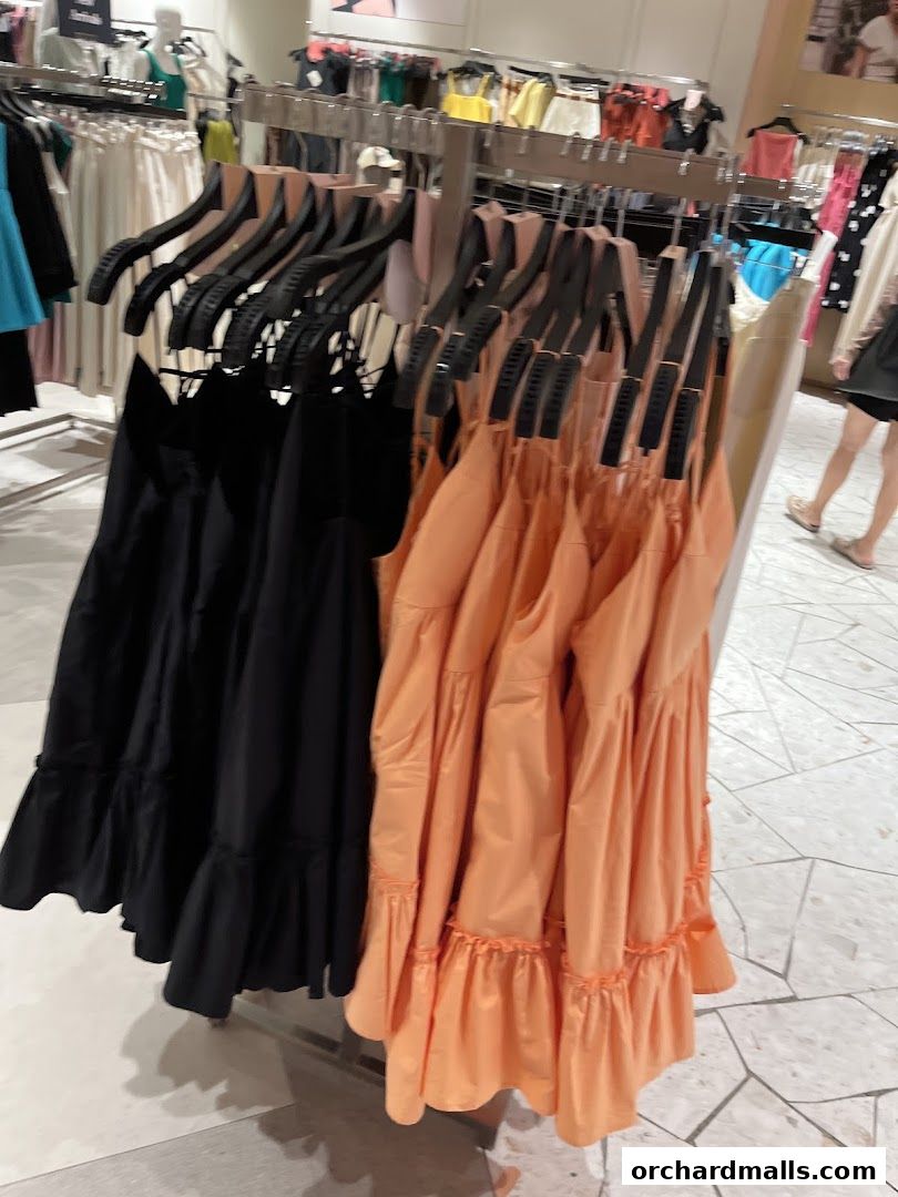 A rack of black and orange dresses with ruffled hems displayed in a clothing store.