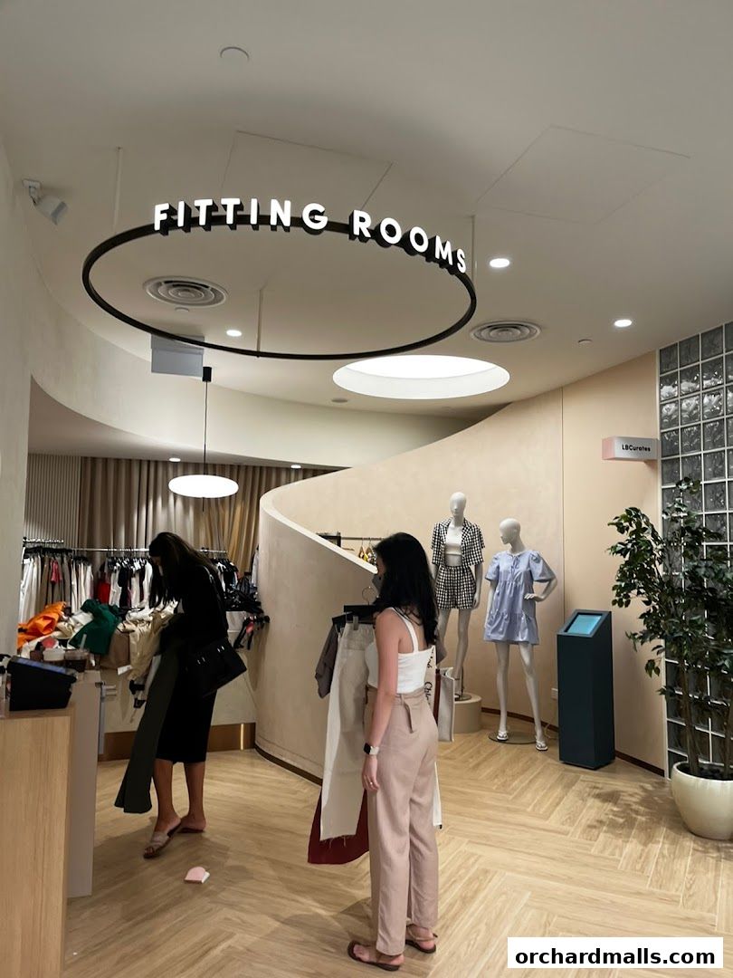 Customers browse clothing inside a modern boutique with fitting rooms and mannequins.