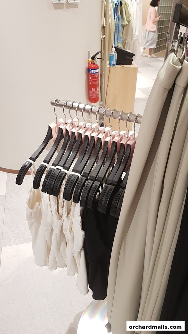 Close-up of clothing racks with white and black tops, and beige outerwear.