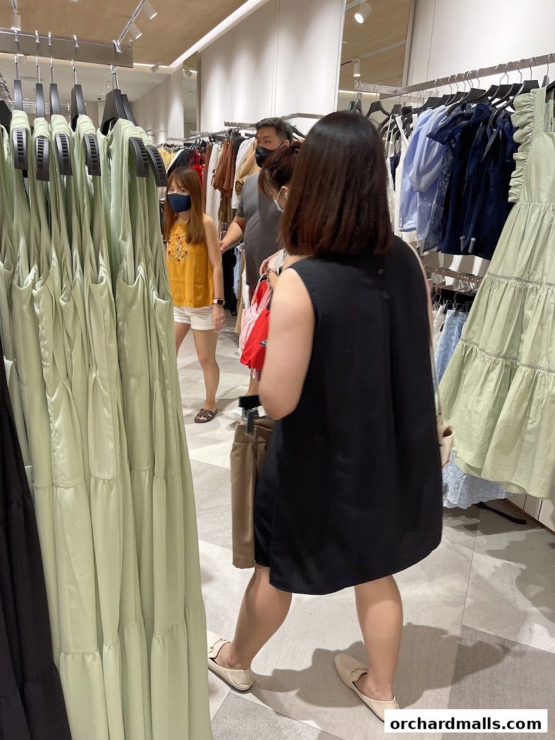 Shoppers browse through racks of stylish women's clothing in a well-lit boutique.