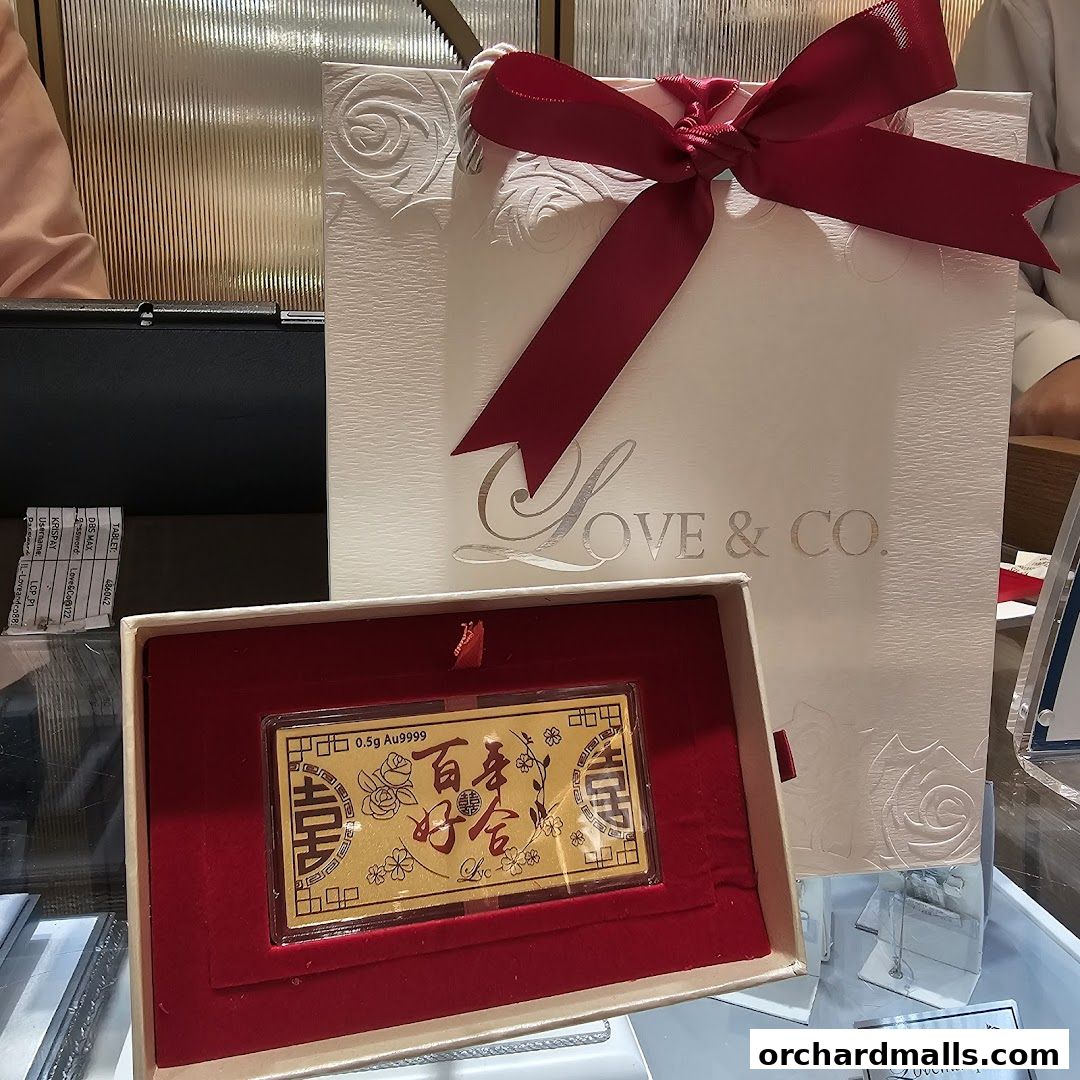 A gold bar with Chinese characters in a red velvet box, next to a gift bag from Love & Co.