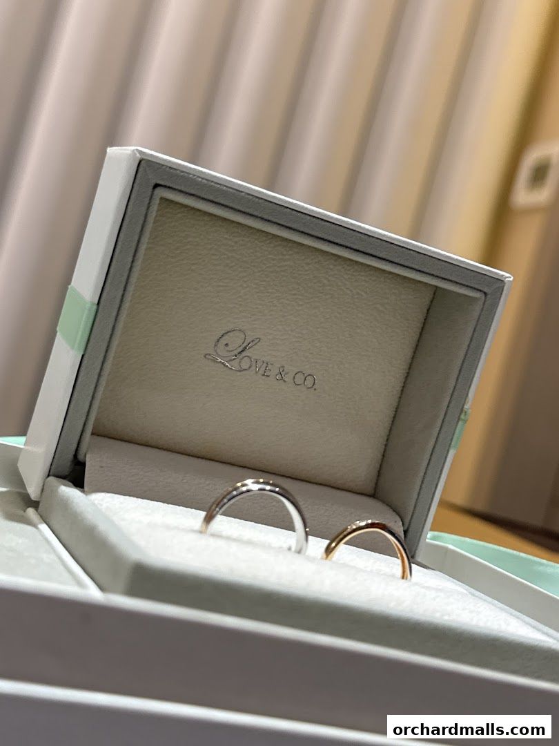 A jewelry box displays two elegant wedding bands, one silver and one gold.