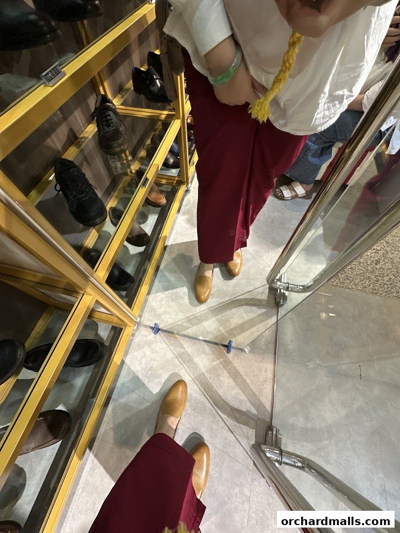 A display of various shoes inside a retail store, with customers browsing.