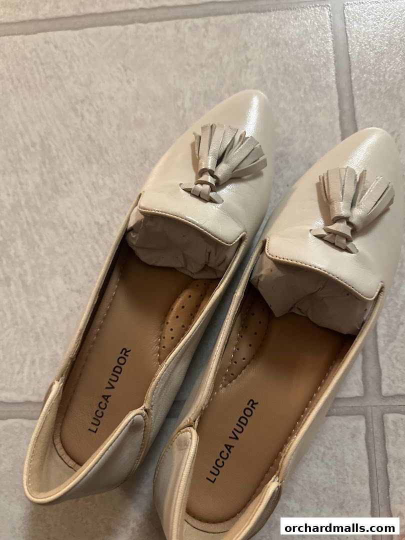 A pair of elegant, cream-colored loafers with tassel details from Lucca Vudor.