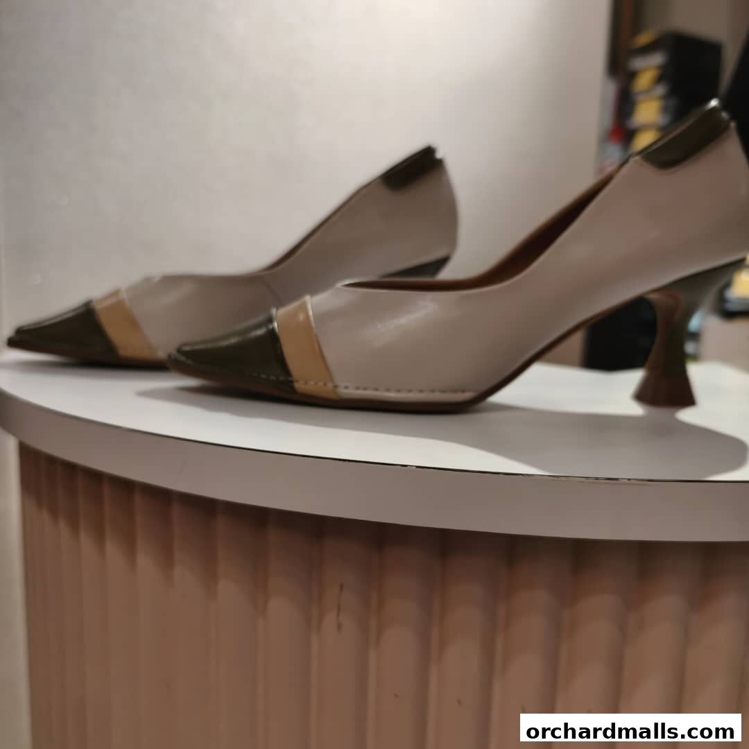 Stylish beige and dark green pointed-toe heels with a unique sculpted heel.