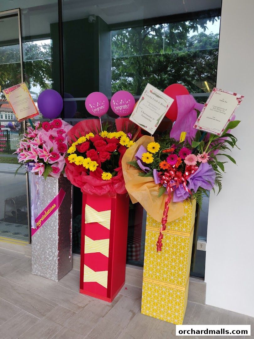 Flower arrangements and balloons outside a shop for a grand opening celebration.