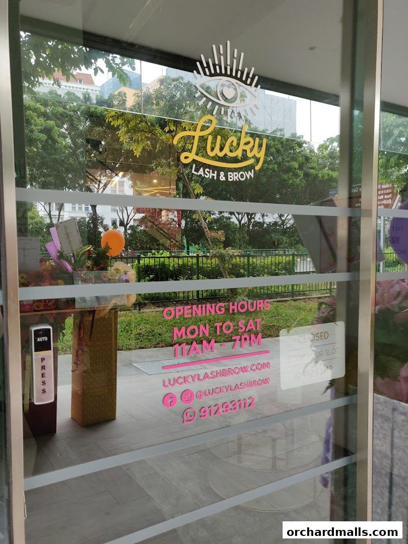 The entrance of Lucky Lash & Brow shop with opening hours and contact details displayed on the glass.