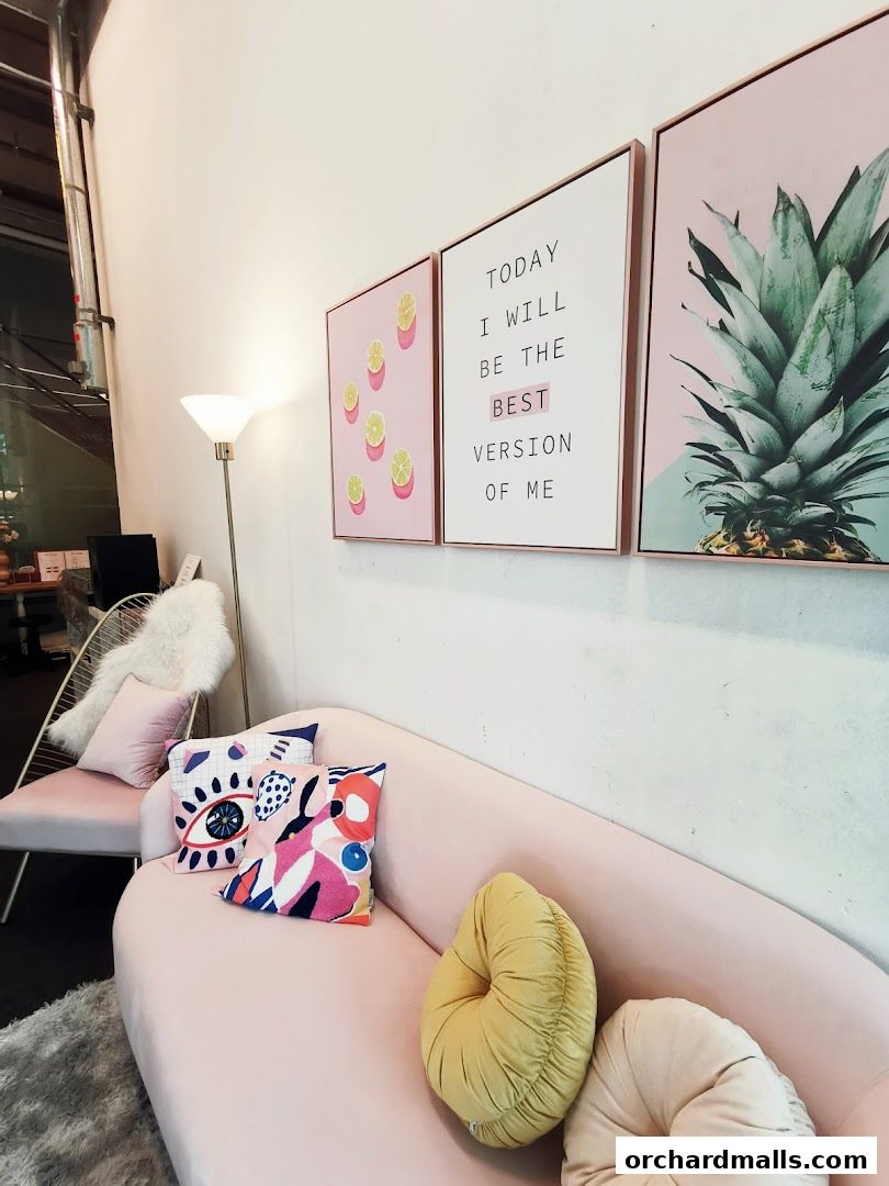 A stylish pink sofa with colorful pillows and inspirational wall art.