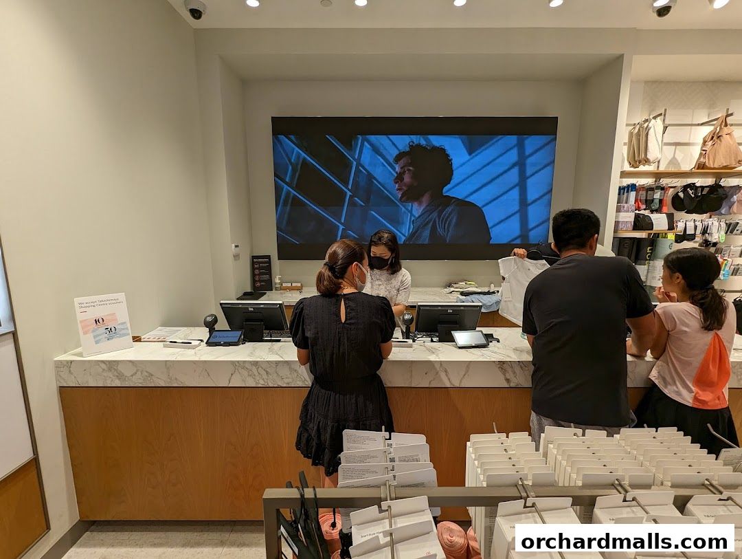Customers interact with staff at the checkout counter of a lululemon store.