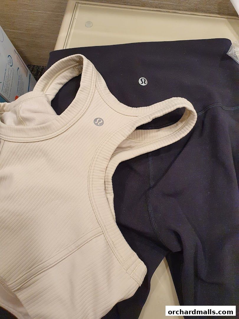 A close-up of a beige ribbed sports bra and black leggings from Lululemon.