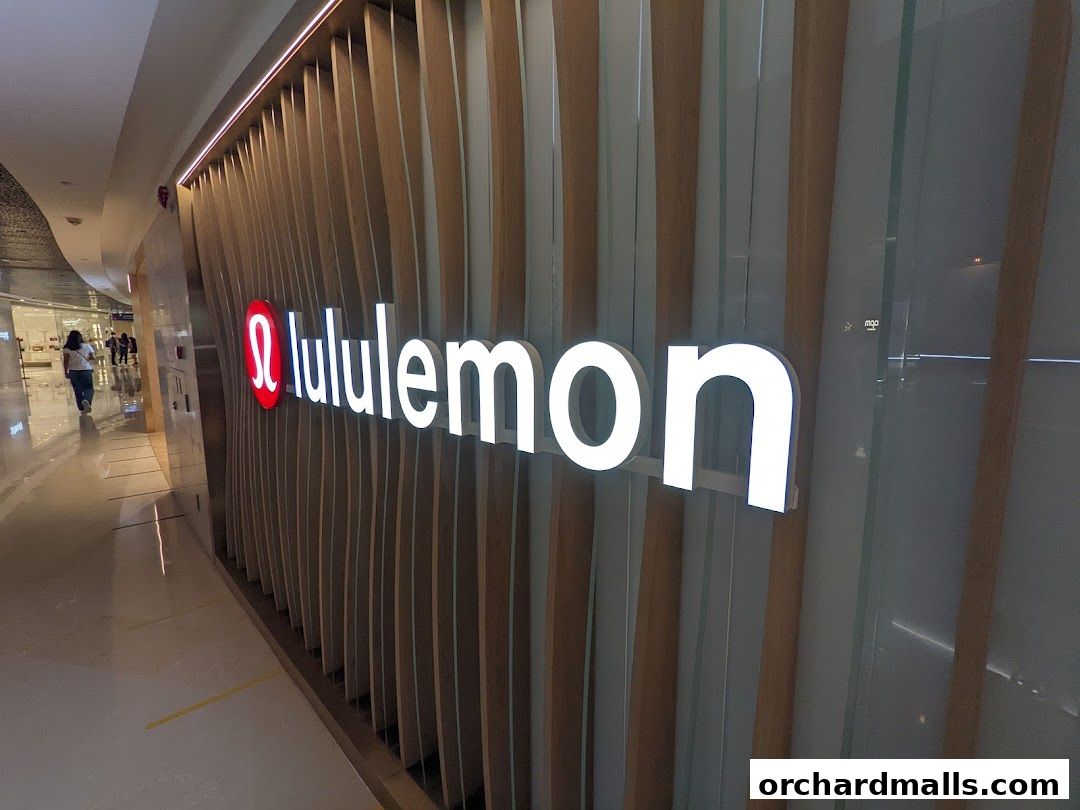 The illuminated Lululemon logo and name are displayed on a modern wooden facade in a mall.