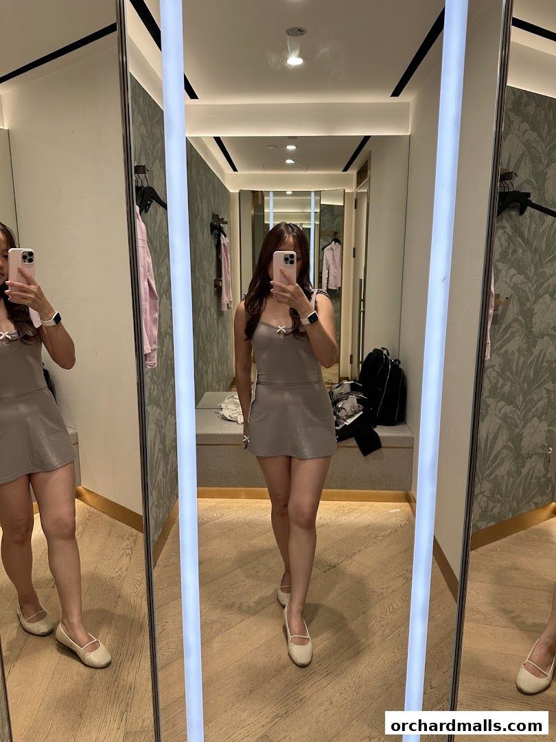 A woman tries on a grey dress in a lululemon fitting room.