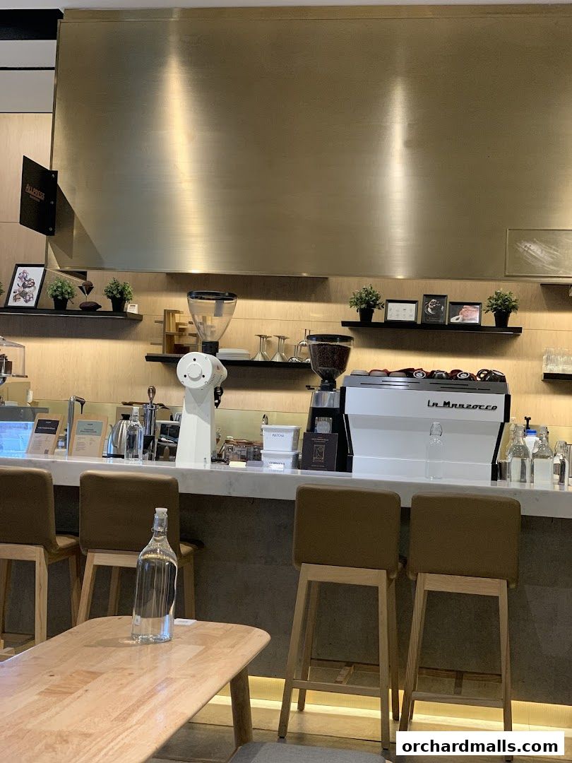 A modern coffee bar with a La Marzocco espresso machine and bar stools.