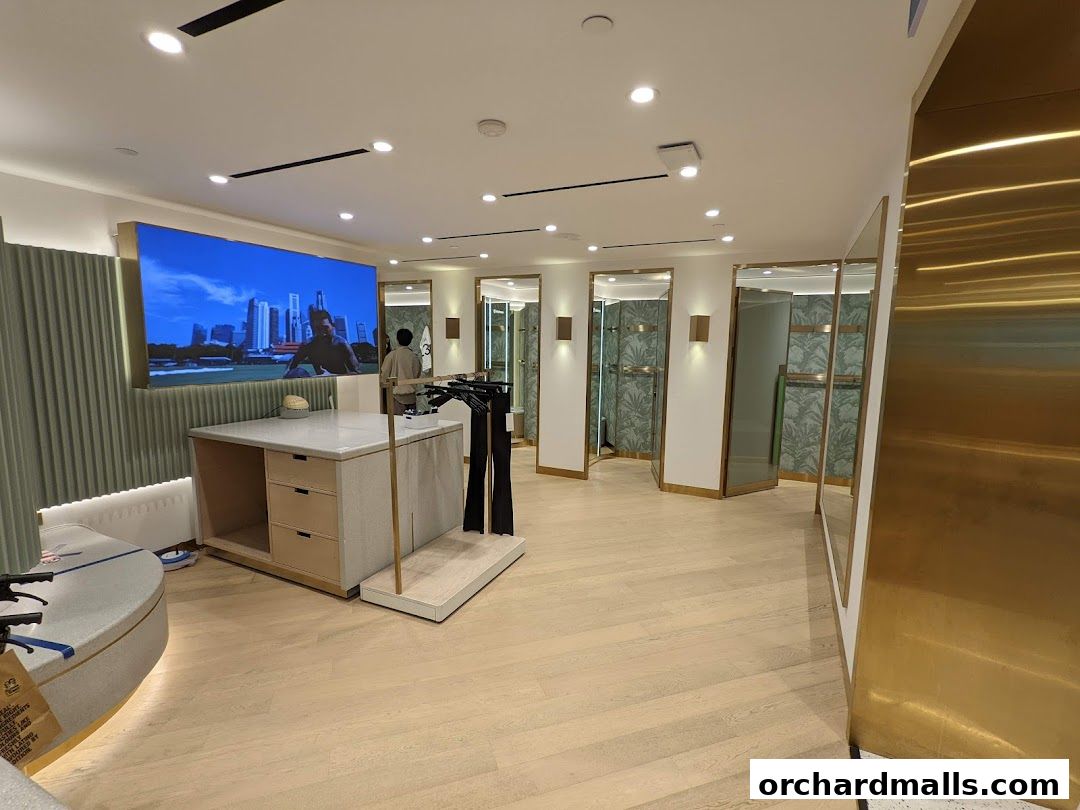 Interior of a lululemon store with fitting rooms, a display table, and a large screen.