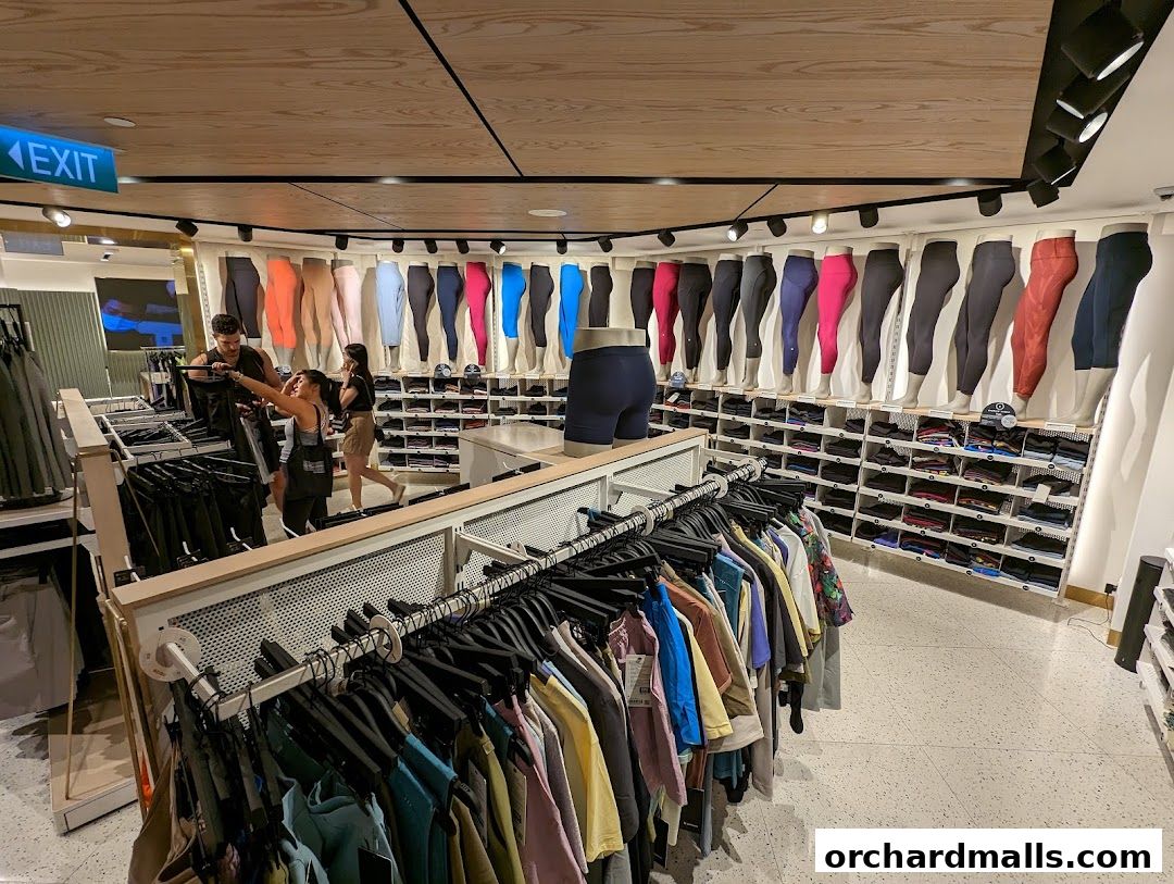 Customers browsing activewear in a brightly lit Lululemon store with leggings displayed on mannequins.