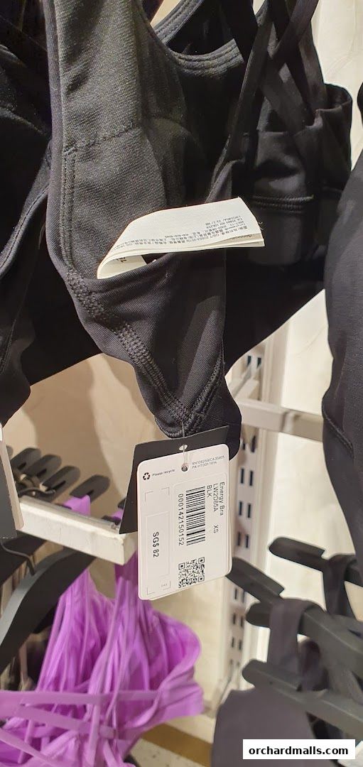 Close-up of black sports bras with tags and a purple sports bra in the background.