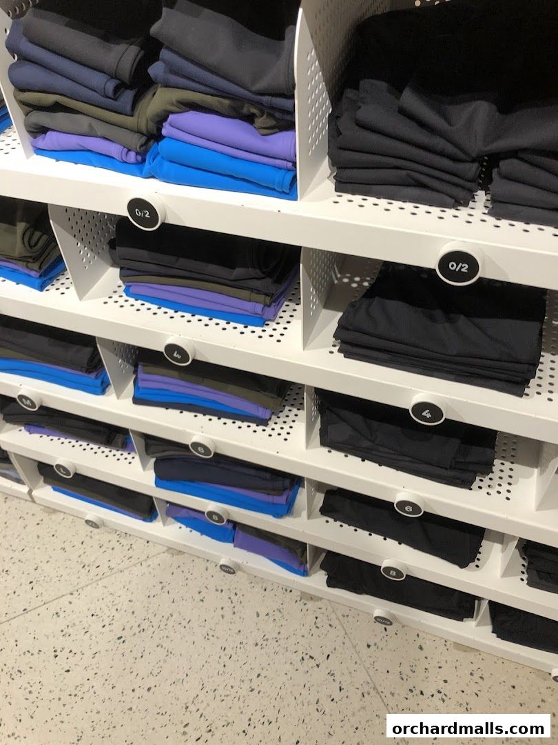 Neatly folded athletic wear in various colors displayed on shelves.