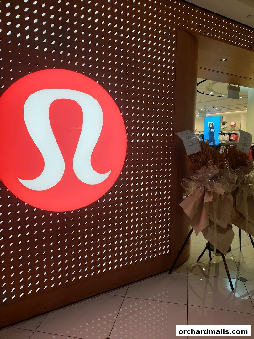 Lululemon store entrance with illuminated logo and decorative displays.