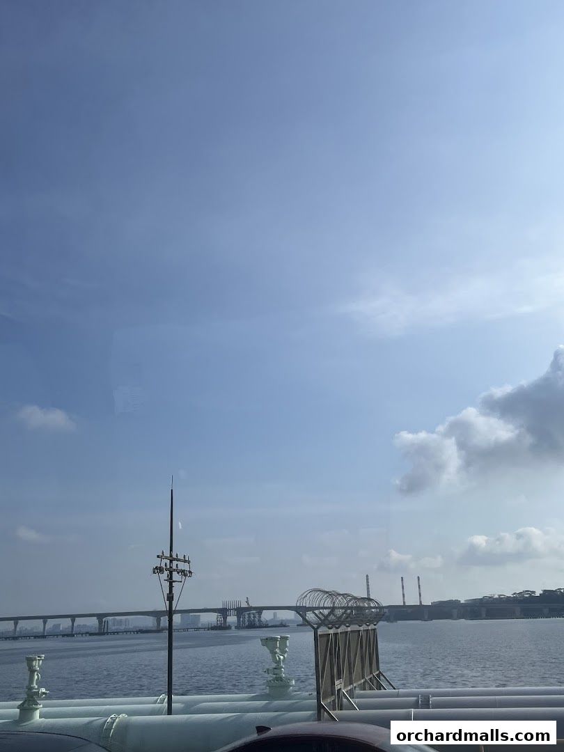 A scenic view of a bridge and industrial structures over a body of water.