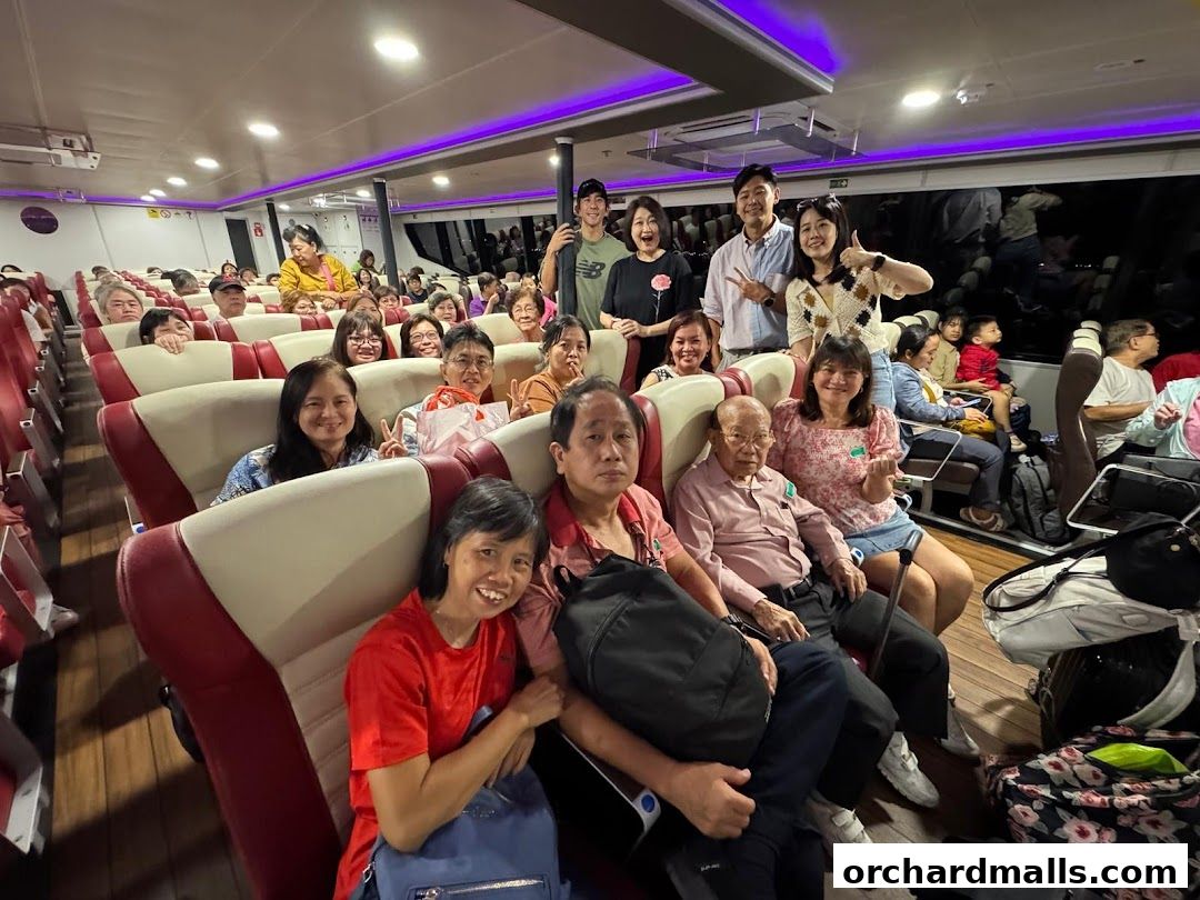 A group of people are seated on a ferry, smiling and posing for the camera.