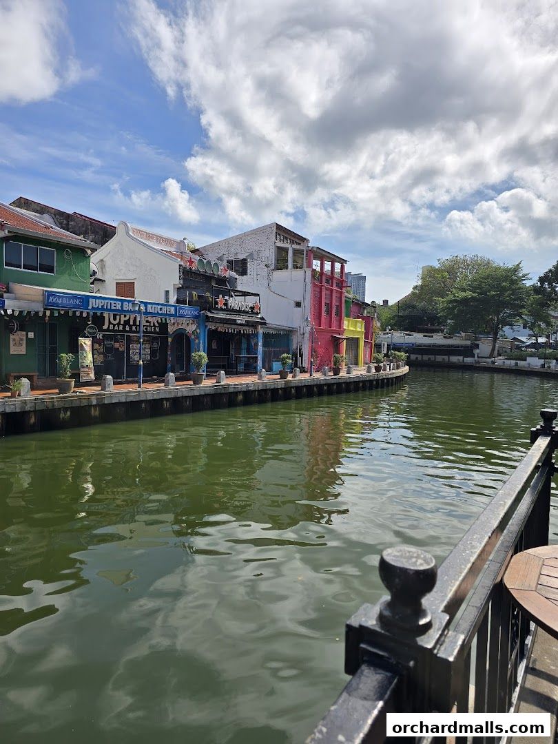A row of colorful shops and restaurants lining a canal under a cloudy sky.
