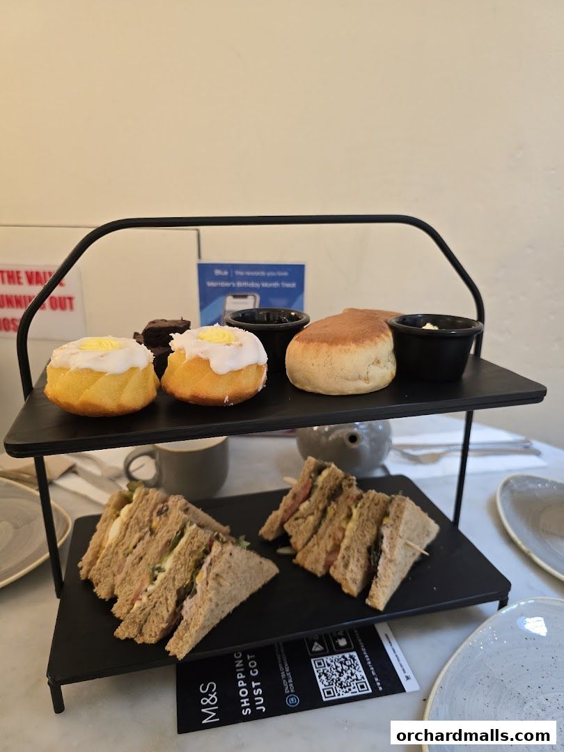 A tiered stand displays sandwiches, scones, and cakes, suggesting a delightful afternoon tea.