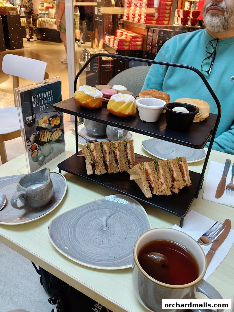 A table set for afternoon tea with sandwiches, pastries, and tea.