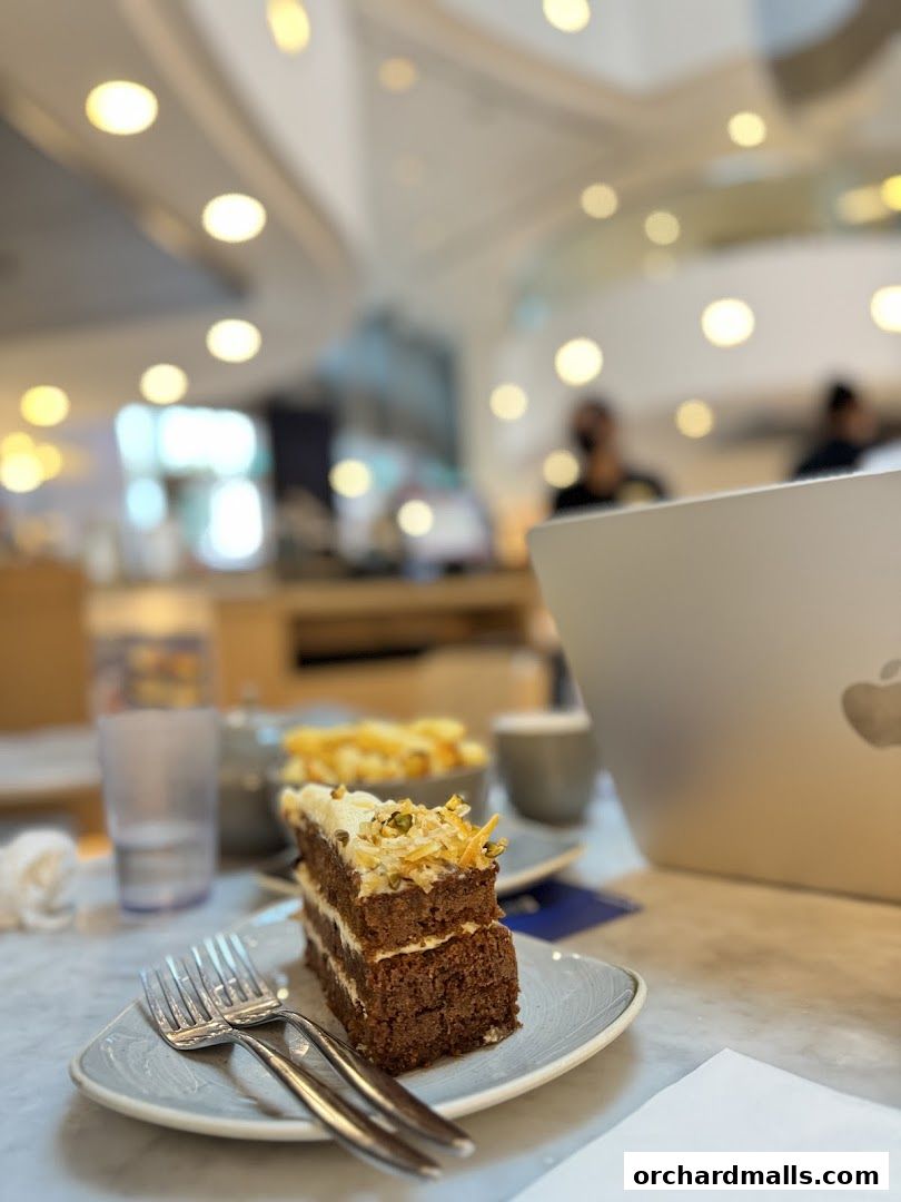 A slice of carrot cake with frosting and nuts on a plate with forks.